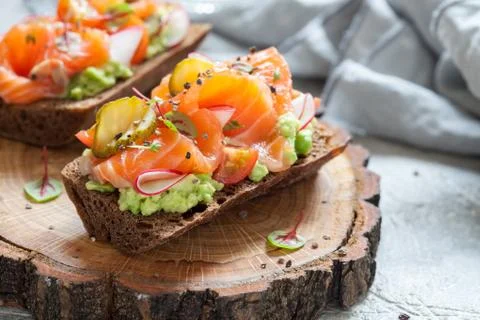 Smorrebrod with salmon on rye bread with vegetables and herbs Stock Photos