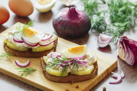 Smorrebrod. A sandwich of rye bread with herring, potatoes, egg, red onion, dill Stock Photos