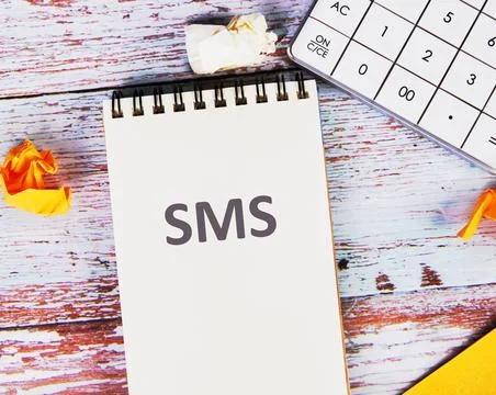 SMS, short message service in a notebook next to a calculator and crumpled st Stock Photos
