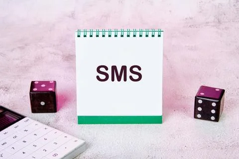 SMS, short message service on a notepad on the table next to a calculator and Stock Photos
