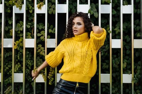 Sn down her back against the wall with green leaves girl in bright clothes Stock Photos