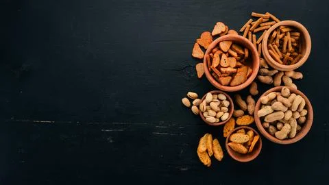 Snack for beer. Salted crackers, chips, nuts, peanuts, pistachios. On a woo.. Stock Photos