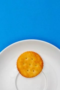 Snack concept, Salty crackers or biscuit in white plate isolated over light b Stock Photos