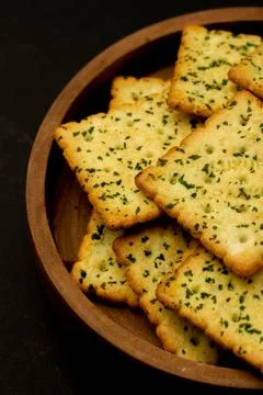Snack concept, Vegetable crackers or biscuits in a wooden plate on black back Stock Photos
