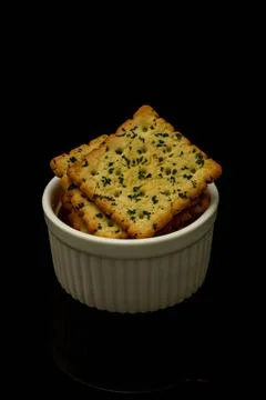 Snack concept, Vegetable crackers or biscuits in a white bowl isolated over b Stock Photos