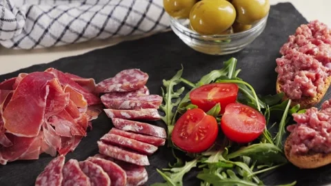 Snack plate beef tartar, cherry tomatoes, green olives and fuet sausage, jamon Stock Footage 315510595