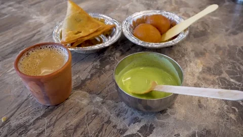 A snack platter featuring samosas, chutney, sweet dessert gulab jamun, and .. Stock Footage 281086680