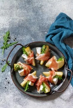 Snacks. Pear appetizer with jamon, arugula and brie cheese. Fotos Stock