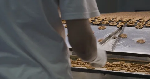 Snacks production Closeup conveyor, worker inspecting baked pretzel snacks Stockbeeldmateriaal 123143617