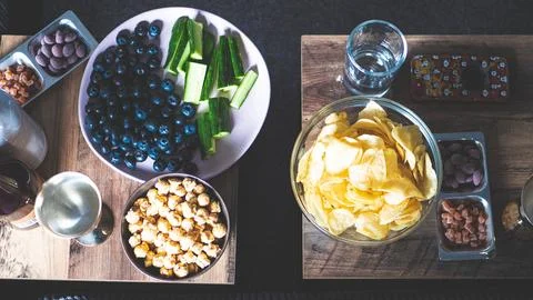 Snacks on a table popcorn and chips crisps cucumbers blueberries Stock Photos