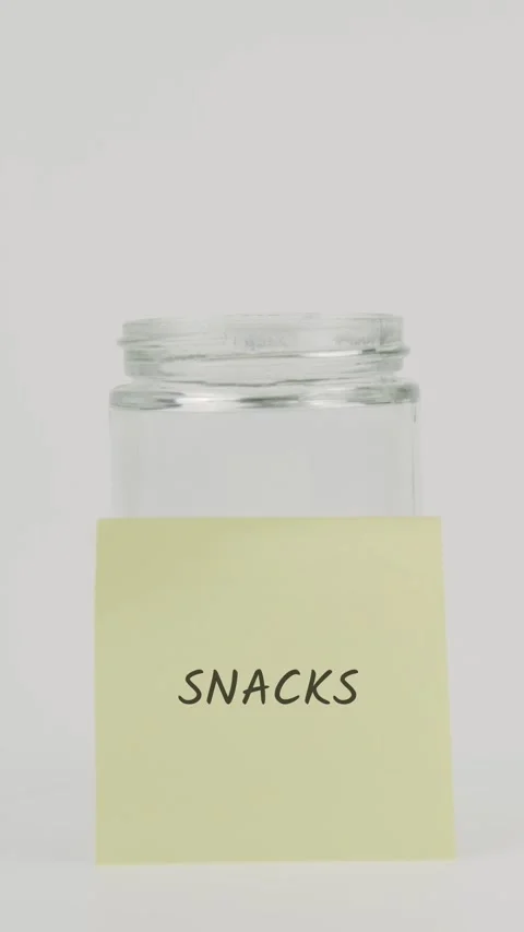 Snacks text or word on yellow sticky note attached to glass jar with hand 스톡 동영상 311787321