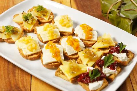 Snacks of toasted bread with Mozarella cheese, fresh cheese and Manchego chee Stock Photos