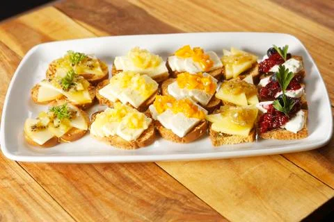 Snacks of toasted bread with Mozarella cheese, fresh cheese and Manchego chee Stock Photos