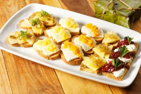 Snacks of toasted bread with Mozarella cheese, fresh cheese and Manchego chee Stock Photos