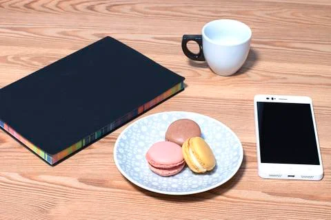 Snak while working from home. Macaroons served on a plate next to a notebook, Stock Photos