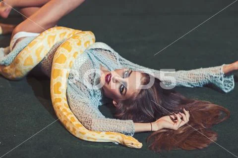 Snake crawl on woman with long hair. Sensual woman relax with albino python Stock Photos