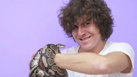 A snake crawls on a man's hand. The man warily looks at the snake Video stock 159055164