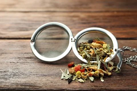 Snap infuser with dried herbal tea leaves on wooden table, closeup Stock Photos