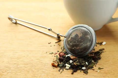 Snap infuser with dried herbal tea leaves on wooden table, closeup Stock Photos
