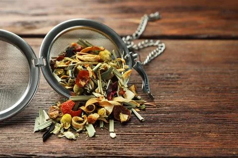 Snap infuser with dried herbal tea leaves on wooden table, closeup. Space f.. Stock Photos