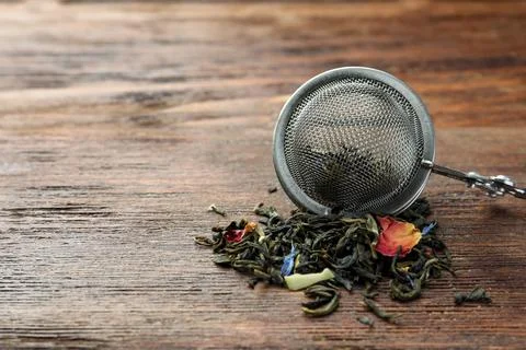 Snap infuser with dried herbal tea leaves on wooden table, closeup. Space f.. Stock Photos
