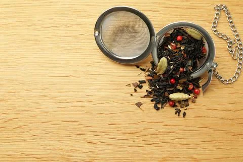 Snap infuser with dried herbal tea leaves on wooden table, top view. Space .. Stock Photos