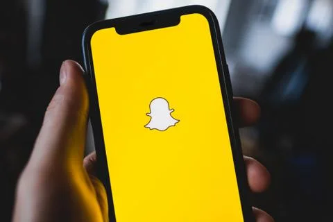 Snapchat app logo on the smartphone screen in hand. Stock Photos
