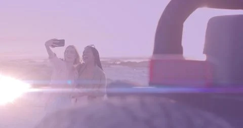 Snapping two friends taking selfie at sandy ocean shore at sunset, with Stock Photos