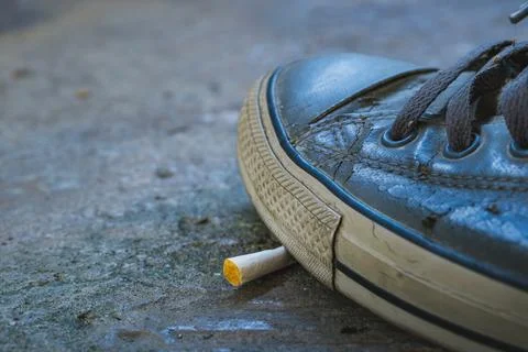 Sneaker crushing cigarette on ground Stock Photos