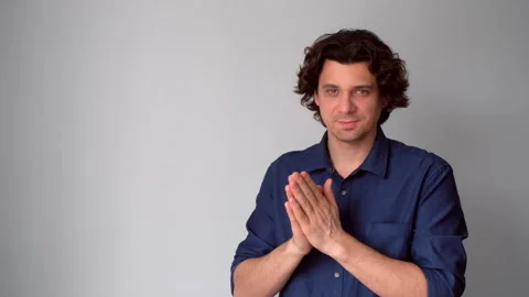 Sneaky scheming curly man rubbing hands plotting cunning idea on gray background Stock Footage 311876131