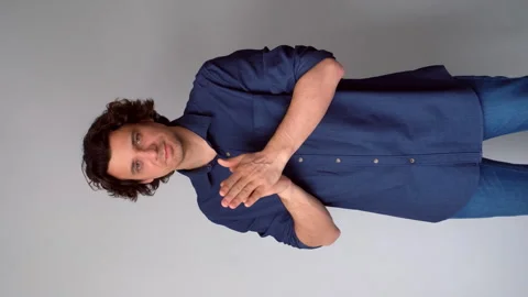 Sneaky scheming curly man rubbing hands plotting cunning idea on gray background Stock Footage 311876505