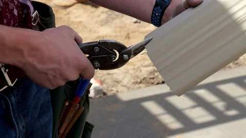 Snip or compound snips are used to cut a section of aluminum rain gutter. Stock Footage 156051384