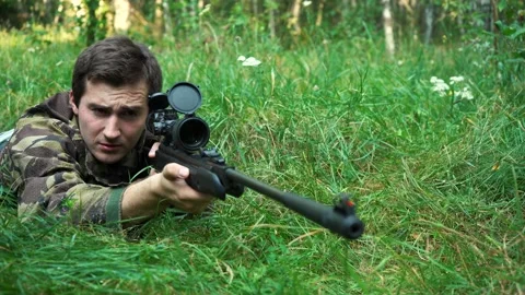 Sniper aim while lying in the bushes. Video stock 165554299