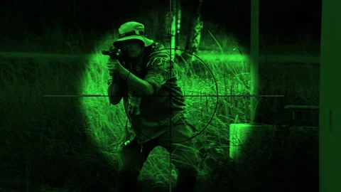 The sniper is aiming to kill the enemy through the scope nightvision Stock Footage 247705231