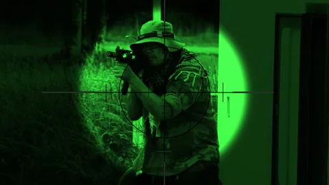 The sniper is aiming to kill the enemy through the scope nightvision Stock Footage 247705285
