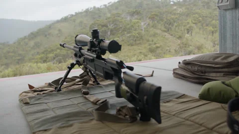 A sniper rifle set up on an hill side lookout, waiting to take aim and shoot. Stock Footage 332780776