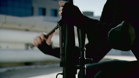 Sniper setting up rifle on a rooftop Stock Footage 289442254