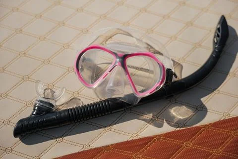 Snorkel equipment resting on patterned boat deck, featuring pink diving mas.. Stock Photos