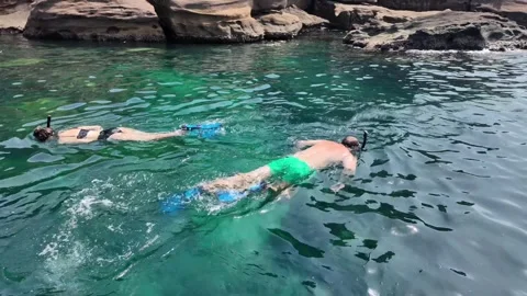 Snorkelers Exploring Turquoise Waters by Cliffs Stock Footage 264994641