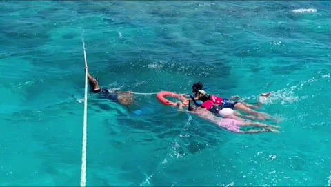 Snorkelers holding lifebuoy pulled by guide on rope over reef in Egypt Stock Footage 341326212
