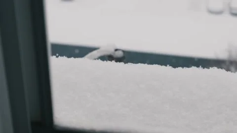 Snow Accumulating on Window Sill with Blurry Winter Scene Outside Stock Footage 327578684