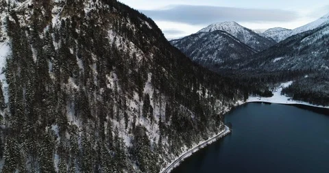 Snow and tree covered mountains with large lake Stock Footage 102487628