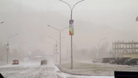 Snow and wind in the city in the spring afternoon on the background of houses an Stock Footage 111499617