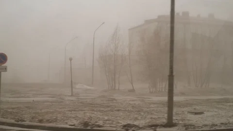 Snow and wind in the city in the spring afternoon on the background of houses an Stock Footage 111499621