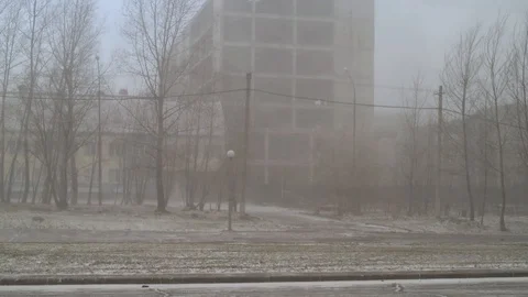 Snow and wind in the city in the spring afternoon on the background of houses an Stock Footage 111499622