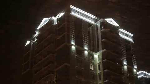 Snow and wind at night on a background of a tall building with illuminated Stock-Footage 60441101
