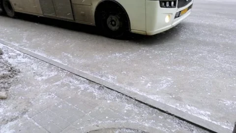 Snow on the asphalt, a bus pulls away. A bus pulls away from the stop. Stock Footage 185966930