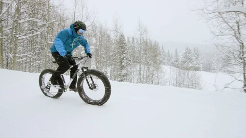 Snow Biker cruising fast down a woodsy path while it snows Stock Footage 113264847