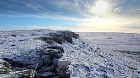 Snow blankets jagged cliffs under a bright, crisp sky 库存影片 347271441