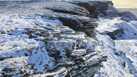 Snow blankets jagged cliffs under soft morning light Vidéo 347274223